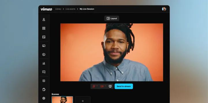 Smiling man in denim shirt is featured in a streamed town hall meeting.