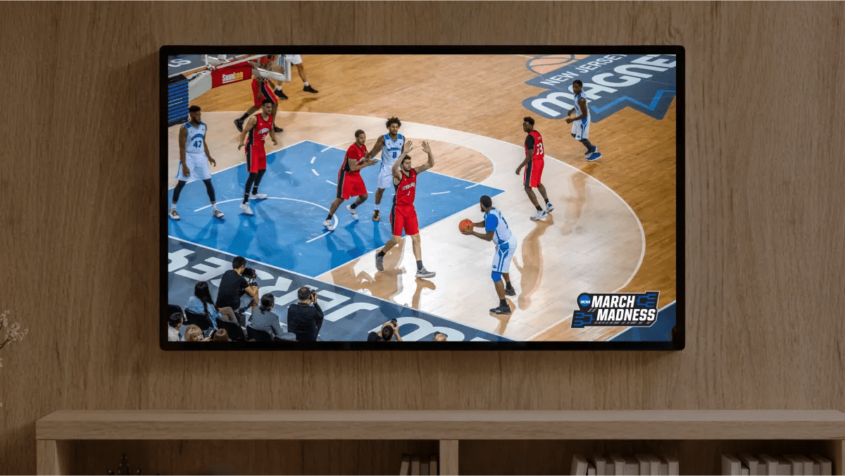 Two basketball teams play each other on a large television on the wall in someone's home.